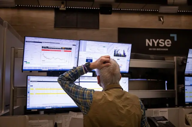 Un hombre se rasca la cabeza mientras observa las pantallas con la cotización en la Bolsa de Nueva York.