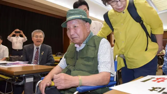 Homem sentado em cadeira de rodas durante audiência judicial