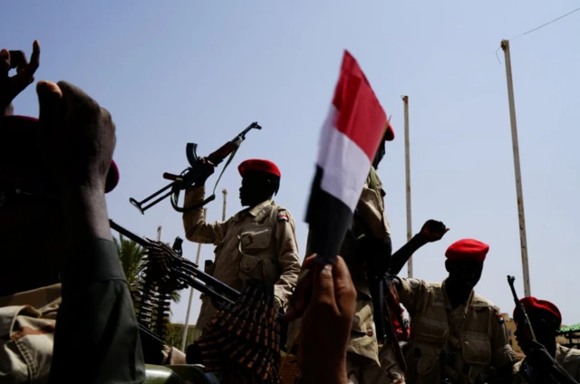 جنود قوات الدعم السريع شبه العسكرية السودانية يحيون الناس أثناء تأمينهم لموقع في الخرطوم