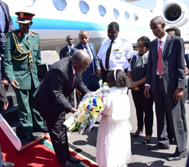 Rais Magufuli akipatiwa shada la maua na mshichana uwanja wa ndege