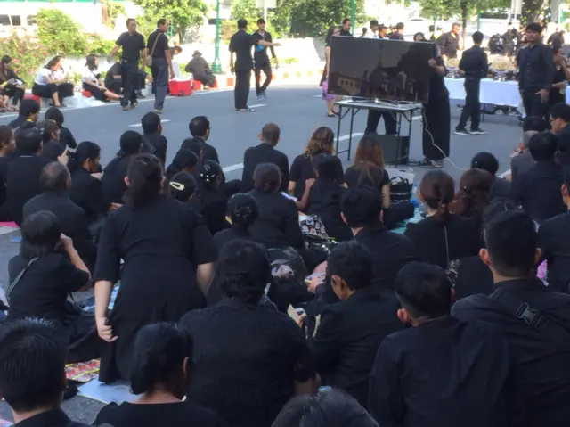 ประชาชนที่เข้าไม่ถึงบริเวณพระราชพิธีนั่งชมโทรทัศน์ริมคลองหลอด หลังกระทรวงกลาโหม