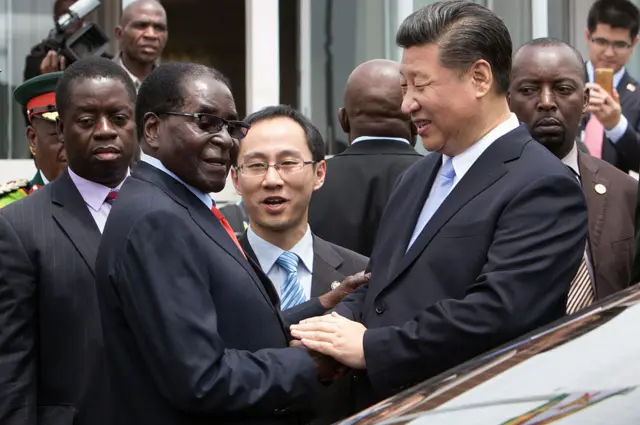 Le président chinois Xi Jinping (D) serre la main du président zimbabwéen Robert Mugabe (G) à son arrivée le 1er décembre 2015 à Harare. Les deux dirigeants ont tenu des pourparlers et supervisé la signature par leurs ministres de 10 accords et mémorandums d'accord couvrant les marchés de l'énergie, de l'aviation, des télécommunications et de la promotion des investissements pour consolider l'économie zimbabwéenne