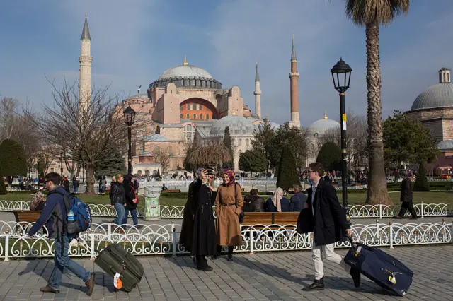 İstanbul Ayasofya Camii'nin önünde turistler bavullarını taşıyor.
