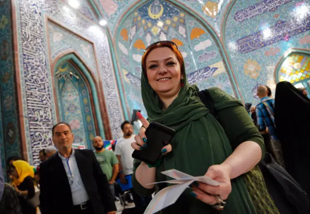ناخبة إيرانية ترفع اصبعها المضمخ بالحبر بعد الإدلاء بصوتها في مركز اقتراع بطهران