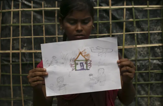كورشيدا، 12 عاما، تحمل رسما تصور فيه ما شاهدته بعينيها قبل فرارها مع عائلتها إلى مخيم للاجئين في بنغلاديش