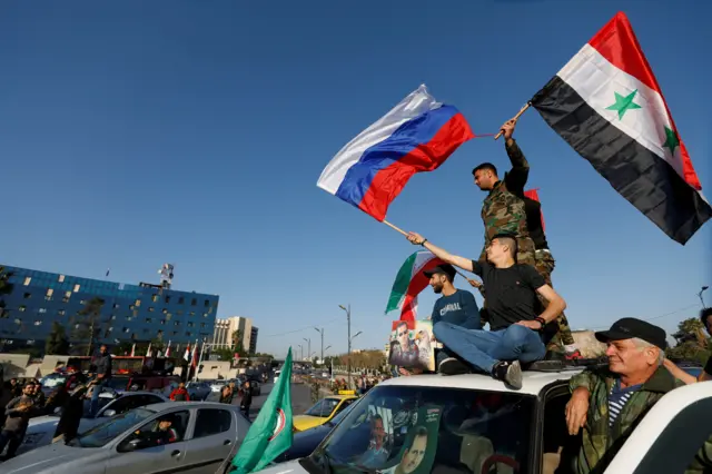 Сирийцы размахивают национальным и российским флагами