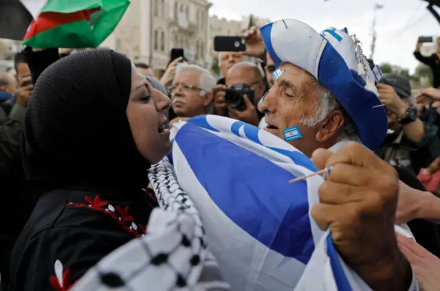 رجل يحمل العلم الإسرائيلي يواجه امرأة فلسطينية تحمل الكوفية عند بوابة دمشق في القدس