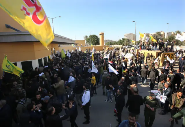 معترضان خشمگین که شبه‌نظامیان گروه‌های وابسته به ایران هم در میان آنها هستند شعار مرگ بر آمریکا سردادند و پرچم این کشور را آتش زدند