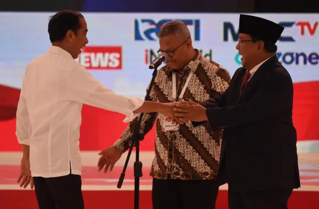 Capres nomor urut 01 Joko Widodo (kiri) dan Capres nomor urut 02 Prabowo Subianto (kanan) bersiap memulai debat capres 2019 disaksikan Ketua KPU Arief Budiman (tengah) di Hotel Sultan, Jakarta, Minggu (17/2/2019).