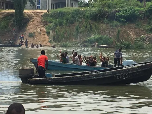 Pipo ontop canoe raise dia hand as dem pass military checkpoint onotp water for Bayelsa