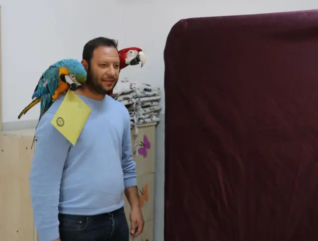 papağanıyla oy veren bir adam