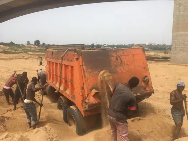 Men wey dey pack sand inside truck