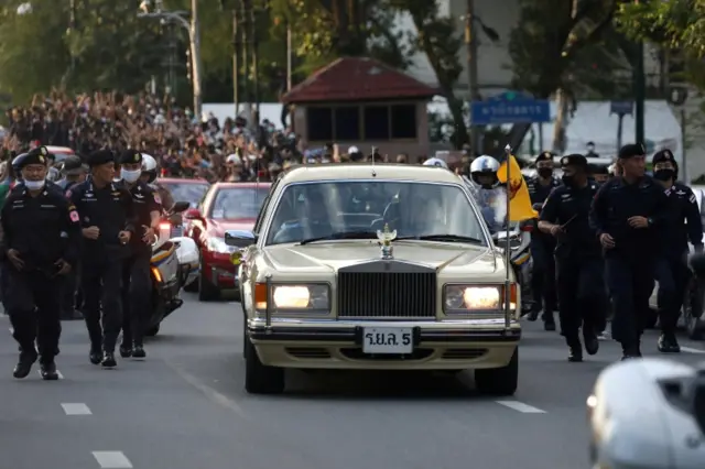 The car carrying Thailand"s King Maha Vajiralongkorn and Queen Suthida drives past a Thai anti-government mass protest