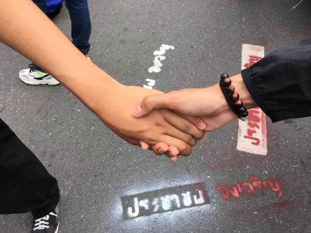การ์ดผู้ชุมนุมยืนจับมือกัน