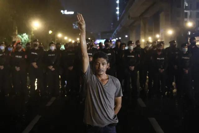 ผู้ชุมนุมบริเวณสะพานหัวช้างยืนชูสามนิ้วด้านหน้าแนวตำรวจ