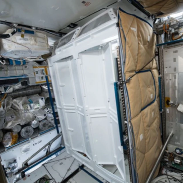The toilet is located inside a stall on the space station