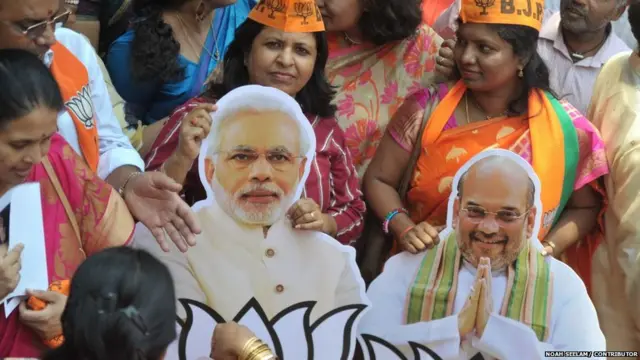 पीएम मोदी और गृह मंत्री अमित शाह को पोस्टर लिए बीजेपी महिला कार्यकर्ता