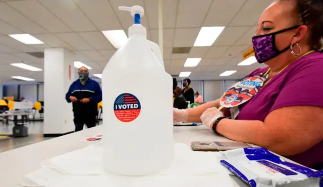 یک محل رای‌گیری در لس‌آنجلس و ژل دست غول‌پیکری که روی آن نوشته من رای دادم