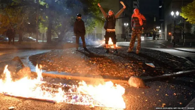 અમેરિકામાં અનેક વિસ્તારોમાં વિરોધપ્રદર્શન પણ થયાં છે. આ તસવીર પોર્ટલૅન્ડની છે જ્યાં અમેરિકાના ઝંડાને આગ ચાંપવામાં આવી છે.