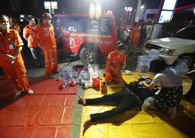 Thai rescue workers help a injured victim after a suspected Thai soldier opened fire in a rampage at the Terminal 21
