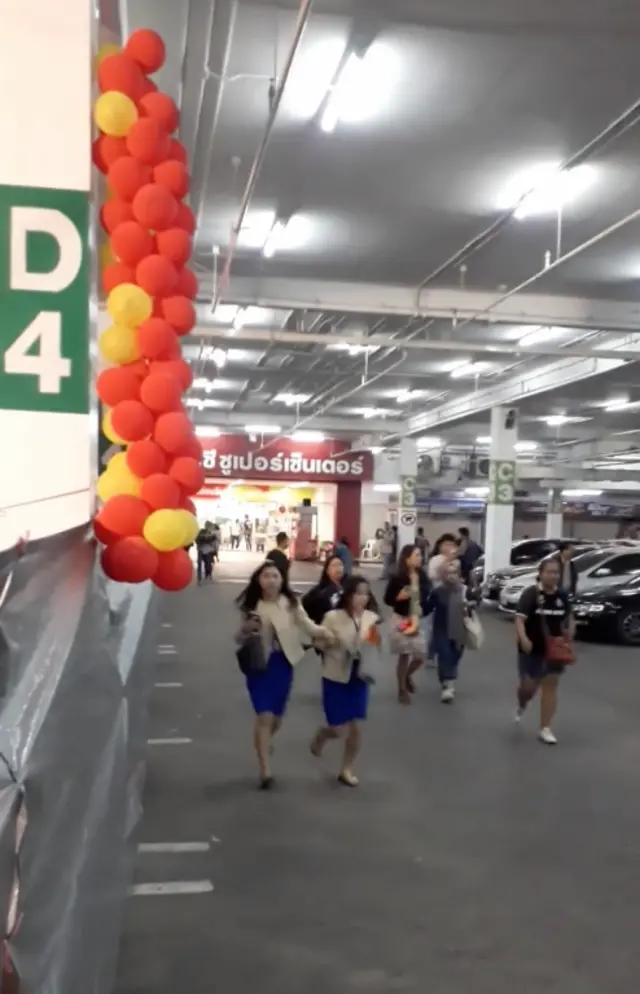 People run away from the shopping mall after a shooting rampage in the city of Nakhon Ratchasima