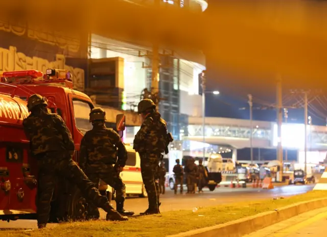 Armed Thai soldiers on guard behind a defensive line, outside the area, after a suspected Thai soldier opened fire in a rampage at the Terminal 21