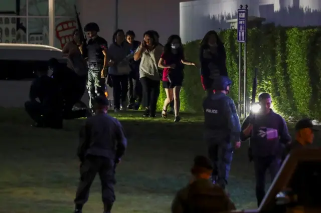 People who were evacuated from a shopping mall speak to each other after a mass shooting at the Terminal 21, in Nakhon Ratchasima