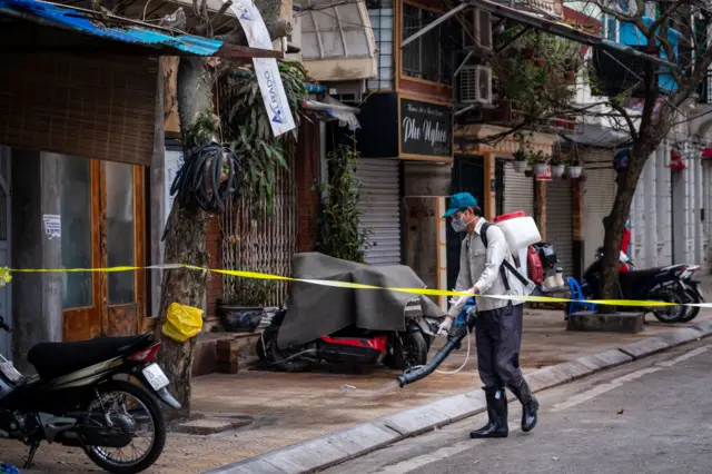 An security man disinfects an area within the quarantined zone of Truc Bach Street on March 10, 2020 in Hanoi, Vietnam.