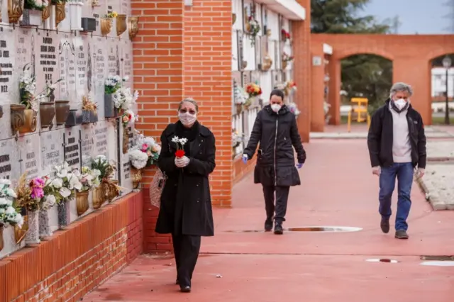 People wearing face masks arrive at the South Municipal cemetery in Madrid, on March 23, 2020.