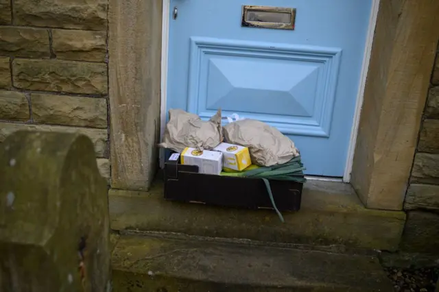 A produce order from the community owned grocery shop, The Village Green, is left on the doorstep of a local resident self-isolating amidst the novel coronavirus COVID-19 pandemic, which has be delivered for free by a volunteer, in Marsden in north-west England, on March 23, 2020.