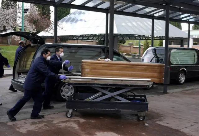 Employees of a mortuary enter the crematorium of La Almudena cemetery the coffin that contains the remains of a person to be cremated during partial lockdown to combat the coronavirus disease (COVID-19) outbreak in Madrid, Spain