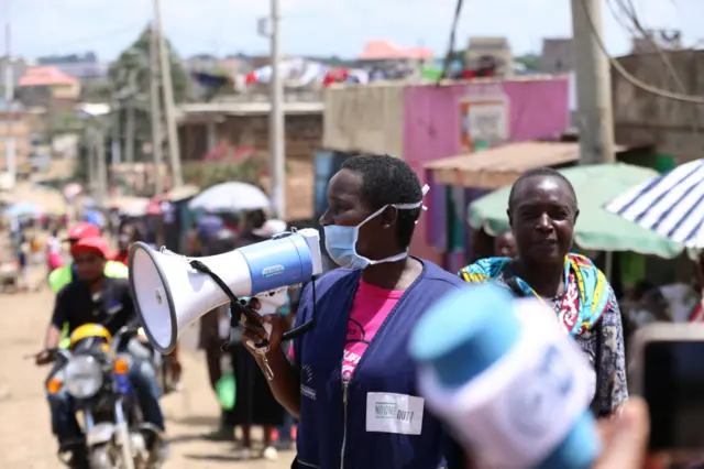 One health volunteer dey waka with megaphone through di streets to sensitising residents about Coronavirus for Baba Dogo slums in Nairobi.