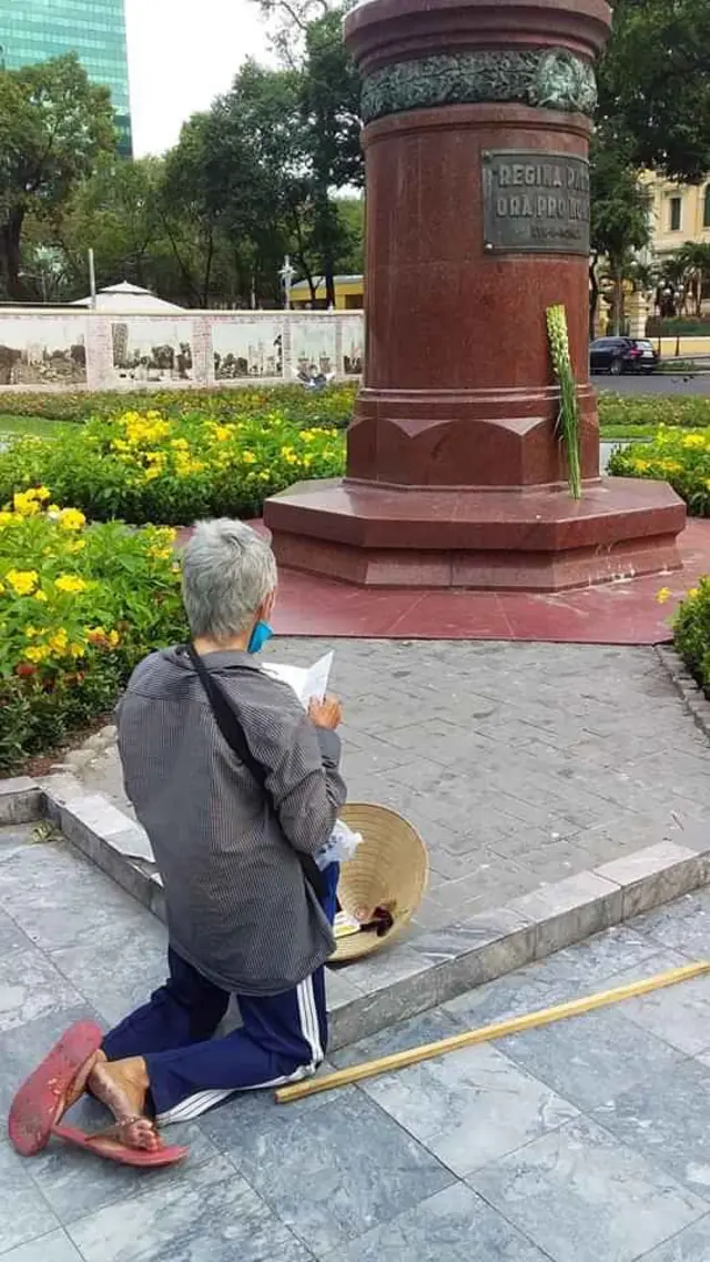 cụ Cụ già cầu nguyện trước tượng Nữ Vương Hòa Bình