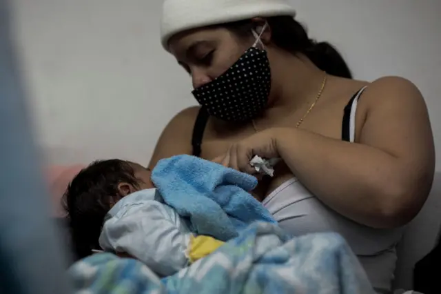 maskeyle bebeğini emziren bir çocuk