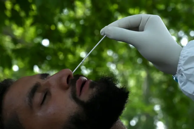 कोरोना वायरस के ख़िलाफ़ जंग लड़ रहे एक स्वास्थ्यकर्मी अपनी जांच के लिए नाक के अंदर से स्वैब का नमूना लेते हुए