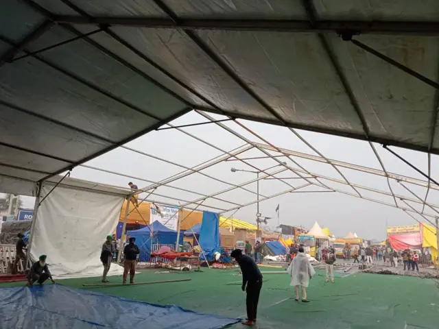 सिंघु बॉर्डर पर वॉटरप्रूफ टेंट लगाते लोग