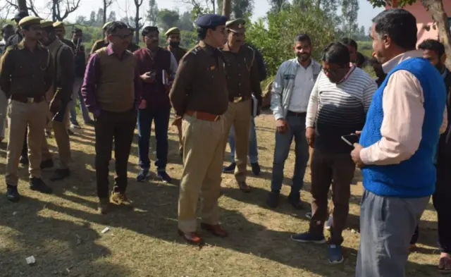 पुजारी की हत्या के मामले में लोगों से बात करते हुए पुलिस अधिकारी