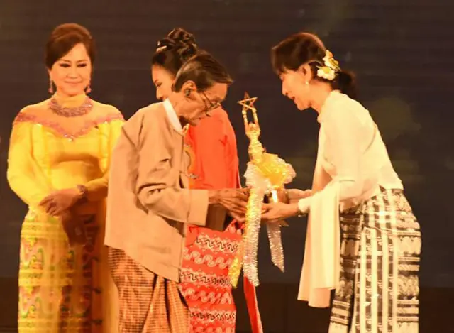 ၂၀၁၈ ခုနှစ်က နိုင်ငံတော်၏ အတိုင်ပင်ခံပုဂ္ဂိုလ် ဒေါ်အောင်ဆန်းစုကြည်မှ မြန်မာ့ရုပ်ရှင် တစ်သက်တာထူးချွန်ဆုအား စည်သူဗိုလ်ကလေးတင့်အောင်အားဆု ချီးမြှင့်နေစဉ်