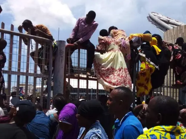 Raia wakiwa wamepanda kwenye uzio ulio kwenye lango kuu la kuingilia uwanjani