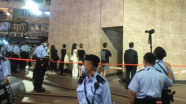 警方截查一些市民，他们面向时代广场的外墙。