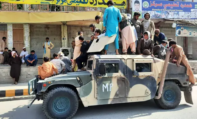 Taliban savaşçıları ve bölge sakinleri Lagman vilayetinde Afgan ordusuna ait bir aracın üzerinde