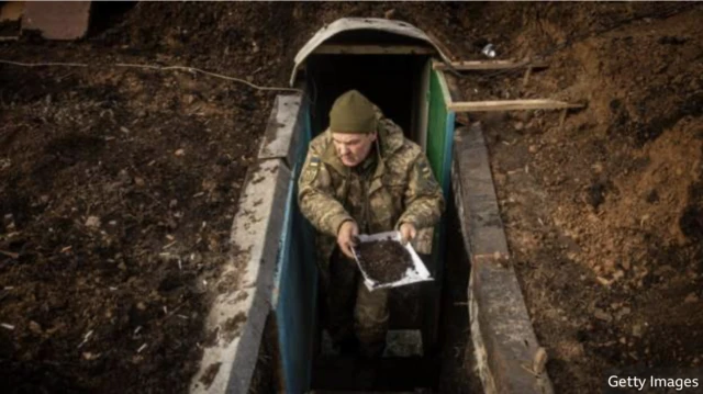 Український військовий прибирає бруд з траншеї на Донбасі
