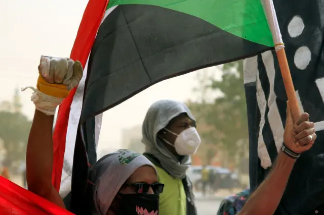 متظاهرون يرفعون العلم السوداني