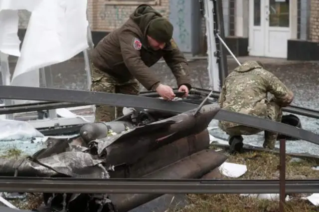 Ukrainian police inspect the remains of a missile that landed in the street in Kyiv
