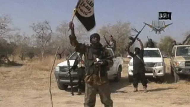 Onew Boko Haram fighter dey hold dia flag plus odas wey surround am wit dia guns