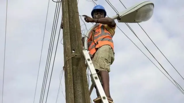 Electricity pole with a linesman on it