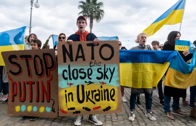 Ukrainian expats hold placards and national flags as the gather to condemn the Russian attack on Ukraine, during a demonstration in the Cypriot coastal city of Larnaca