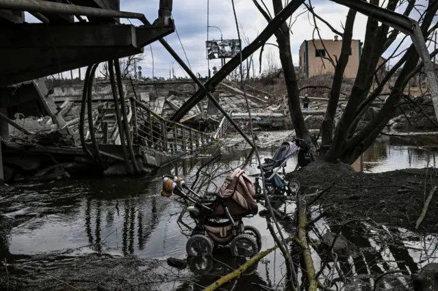 Abandoned strollers are pictured under a destroyed bridge as people flee the city of Irpin, west of Kyiv, on March 7, 2022. -