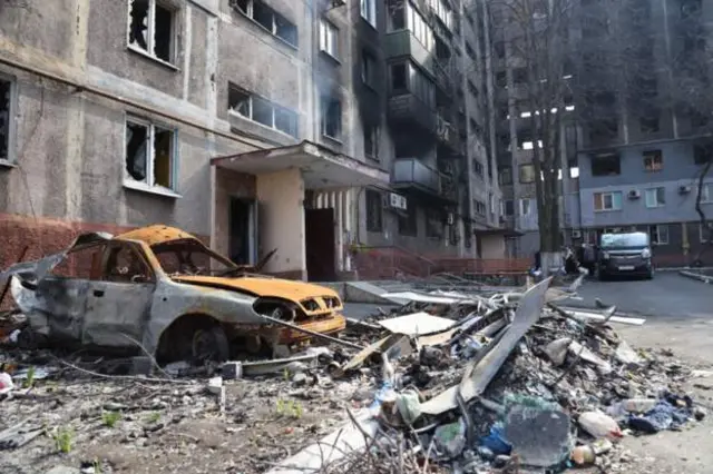 Wrecked car and buildings in Ukraine