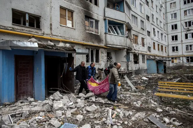 Сотрудники спасательных служб выносят из дома тело убитой женщины в Харькове